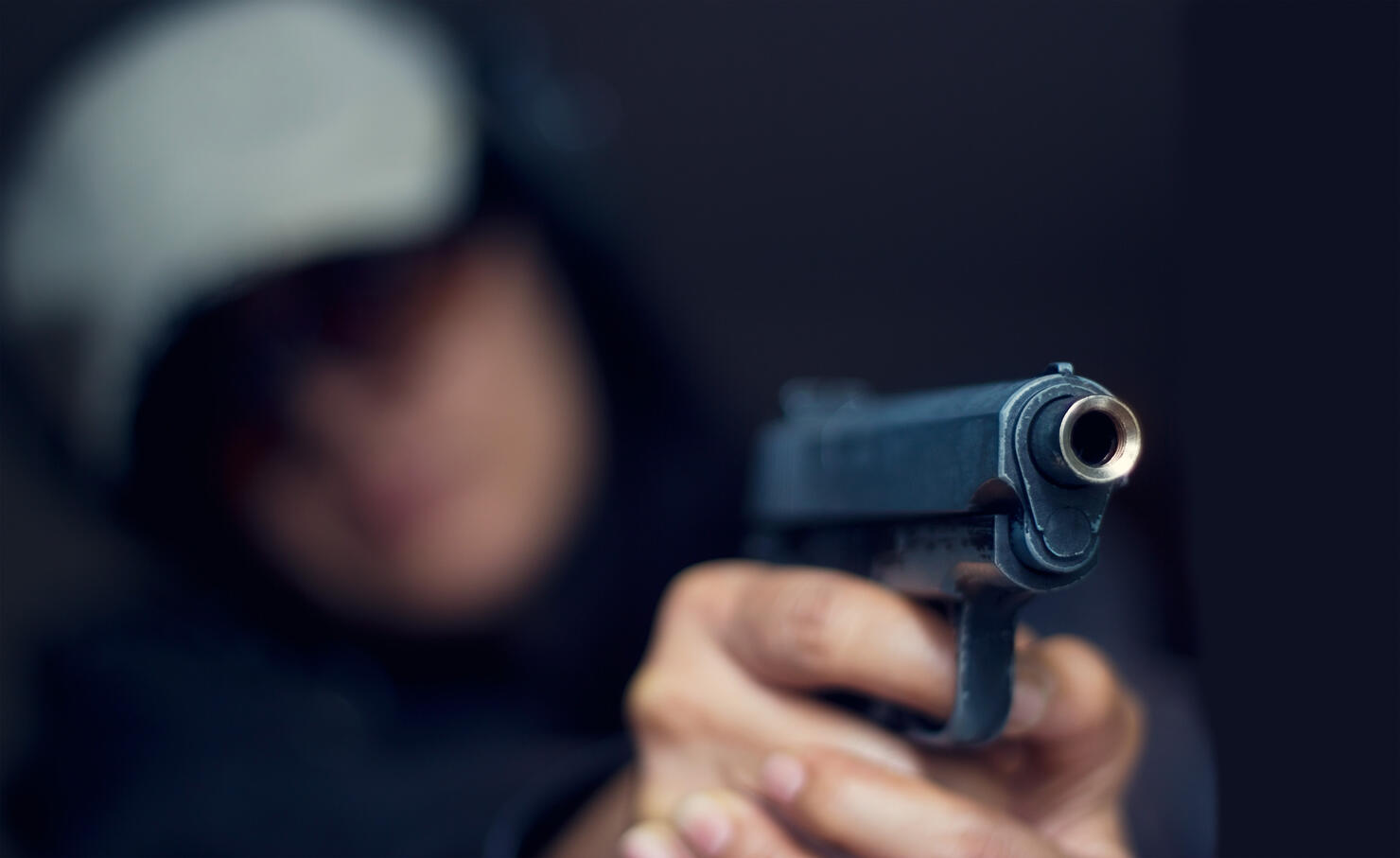 Woman pointing a gun at the target on dark background