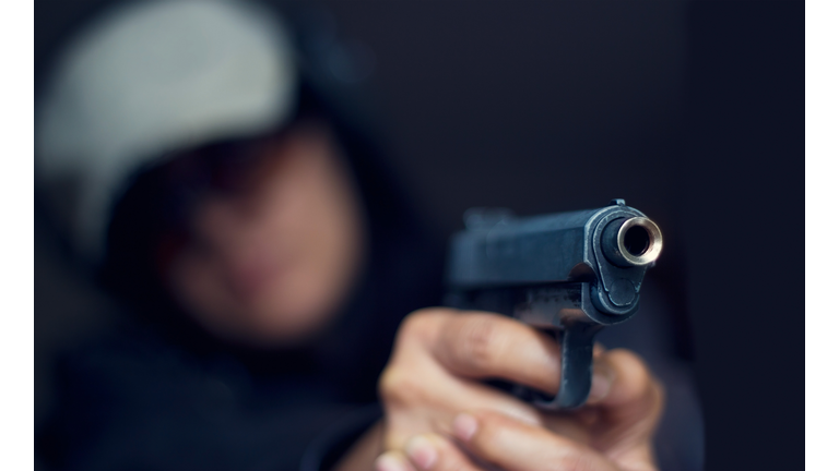 Woman pointing a gun at the target on dark background
