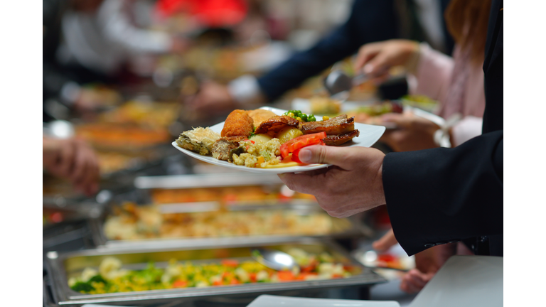 People in a buffet line with full plates