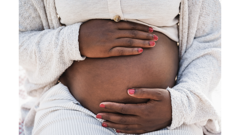 Close up of african pregnant woman holding her belly - Focus on hands