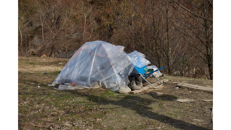 Parking of the homeless on the bank of a mountain river. The tent is covered with plastic wrap.