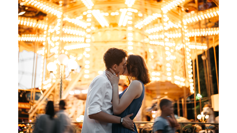 Couple kissing near the marry-go-round in the park