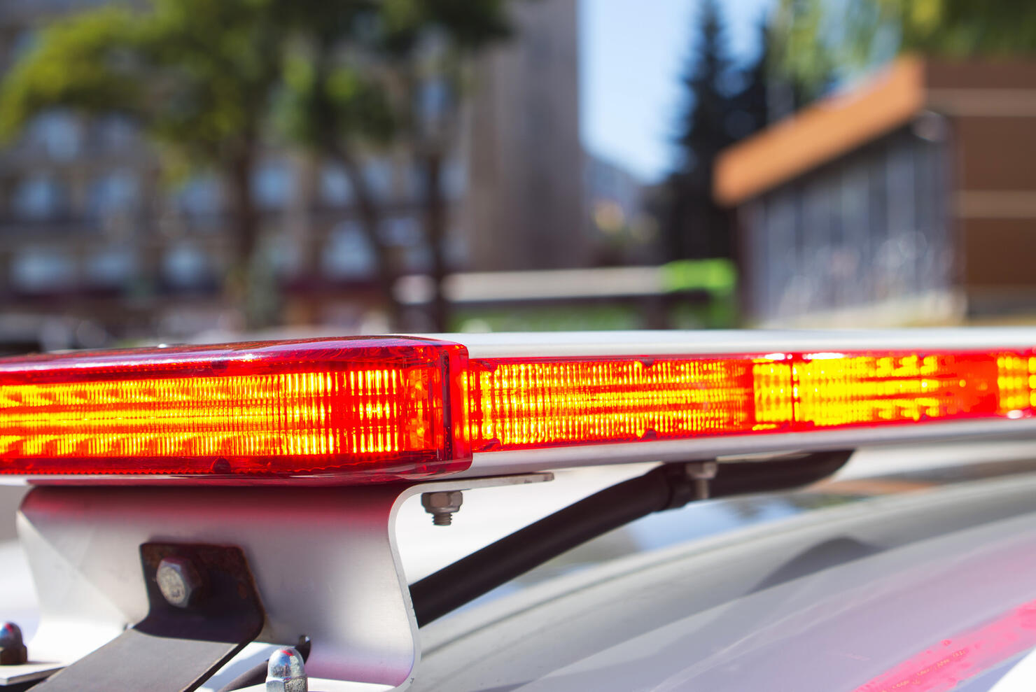 Red police car lights or emergency lights on street background. A part of red flasher on the roof of police car, crime scene, patrolling the city. Selective focus, close-up.