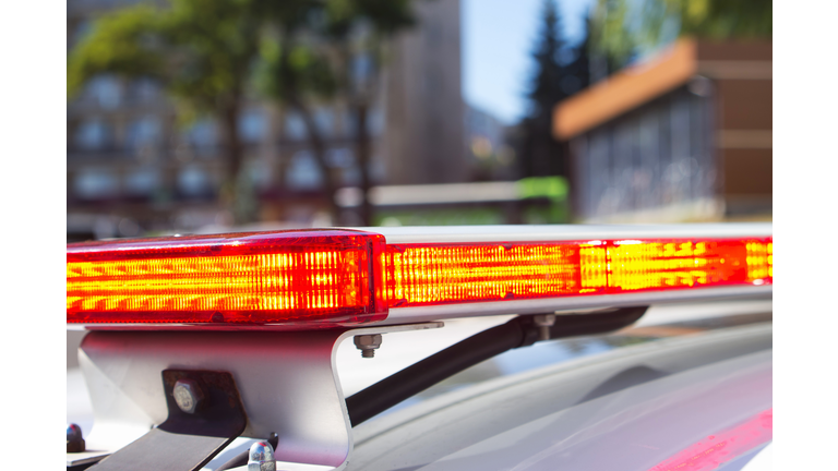 Red police car lights or emergency lights on street background. A part of red flasher on the roof of police car, crime scene, patrolling the city. Selective focus, close-up.
