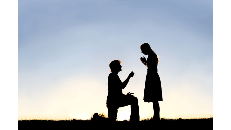 Silhouette of Young Man with Engagement Ring Proposing to Woman