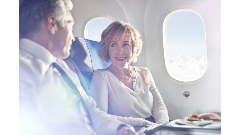 Businessman and businesswoman talking in first class on airplane