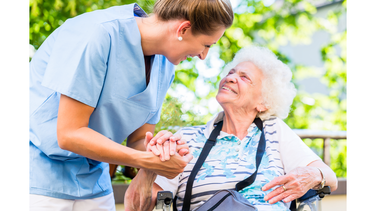 Nurse holding hand of senior woman in pension home