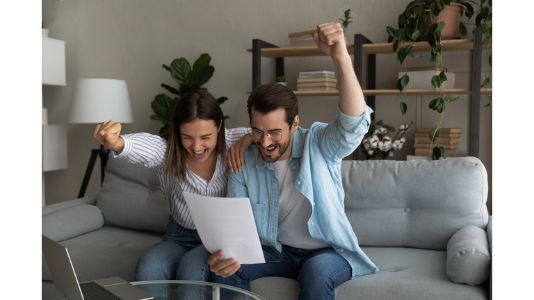 Excited young married couple getting money grant for family business