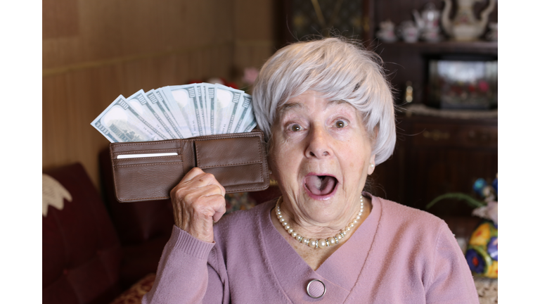 Surprised senior woman with full wallet