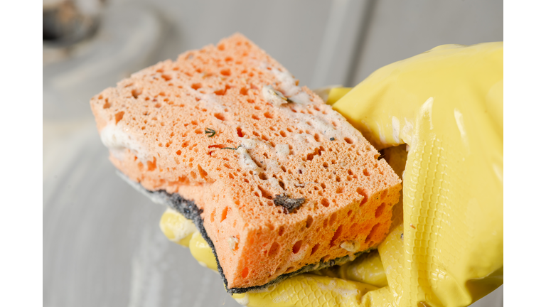 Close-up of hand in a yellow glove with sponge.
