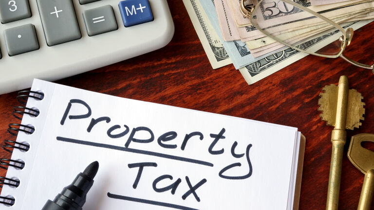 Property tax written in a notebook and calculator.