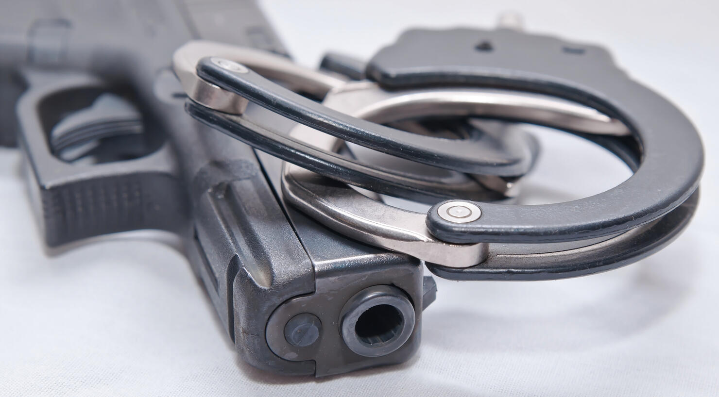 A pair of black and silver handcuffs on top of a black pistol
