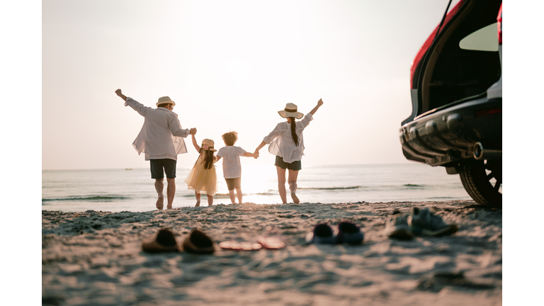 Family vacation holiday, Happy family running on the beach in the sunset. Back view of a happy family on a tropical beach and a car on the side.