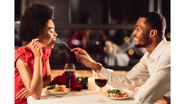 African American Man Feeding Girlfriend Celebrating Anniversary In Restaurant