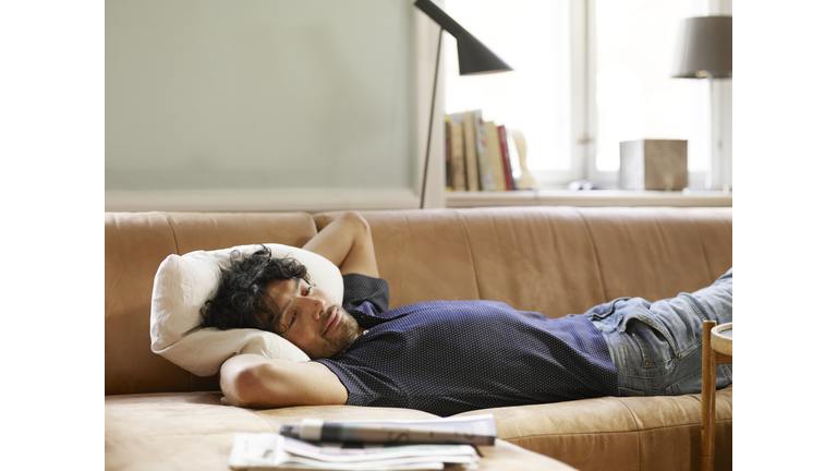 Young man lying on sofa watching TV