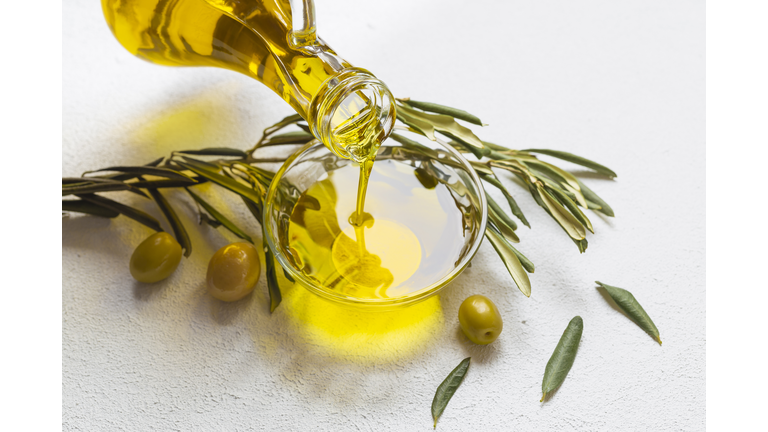 High angle view of olive oil pouring in bowl on table