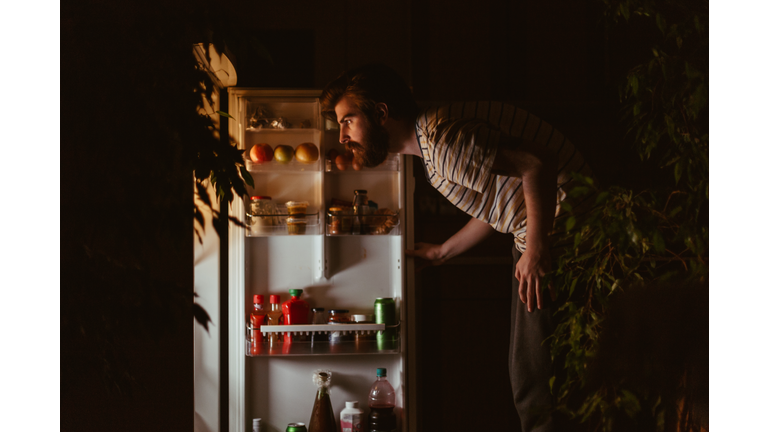 Man looking for snacks in the refrigerator late night