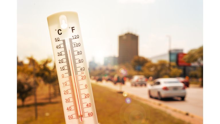 Thermometer in front of cars and traffic during heatwave