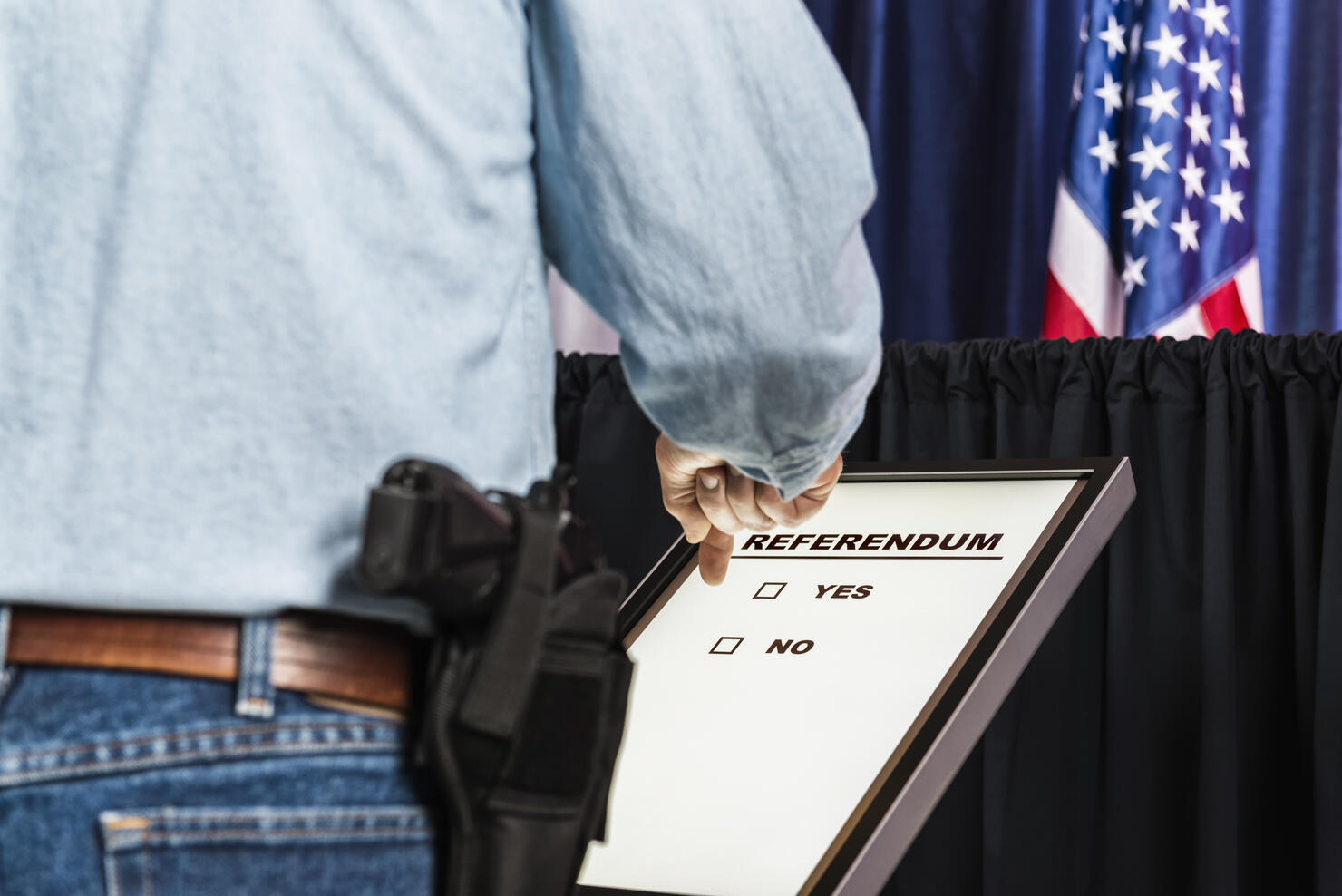 Man with open-carry handgun in holster looking over Referendum ballot