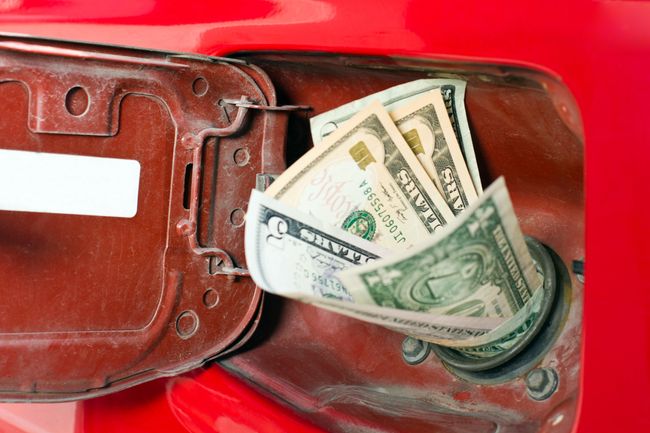 Money in the chute of a gas representing high gas prices