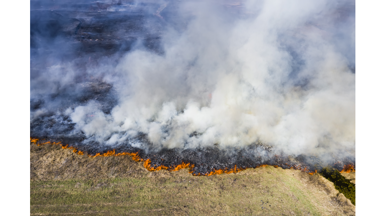 Aerial view of wildfire on the field. Huge clouds of smoke