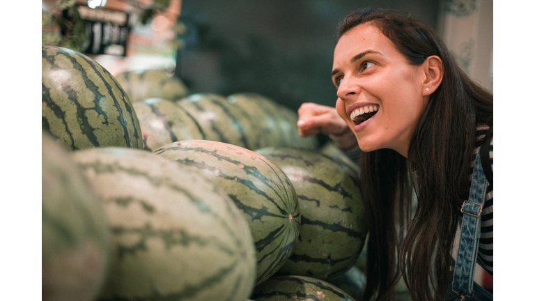 Beautiful young woman buying fresh vegetables in the market