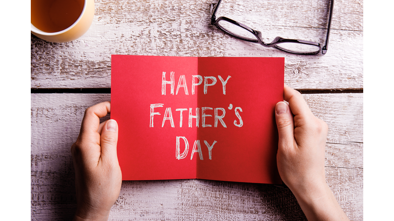 Fathers day composition. Hands of dad holding greeting card