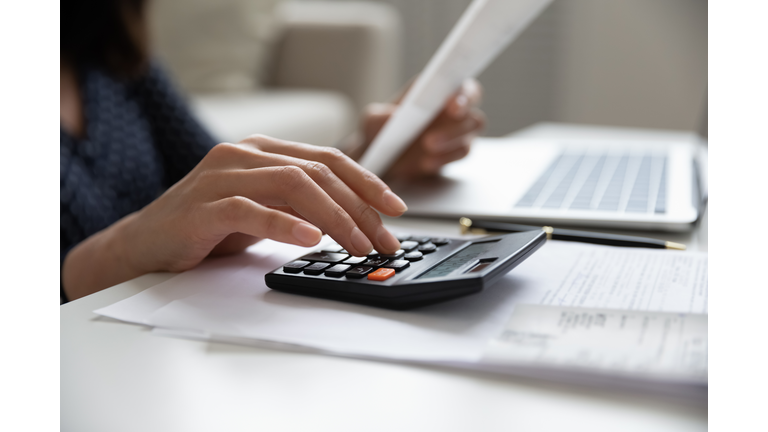 Close up young mixed race woman calculating domestic expenses.