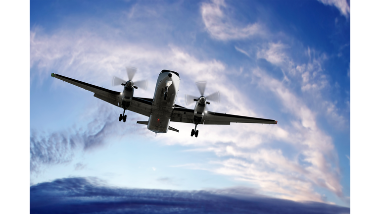 XL propeller airplane landing at sunset