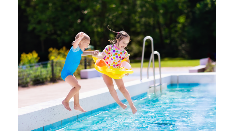 Happy little kids jumping into swimming pool