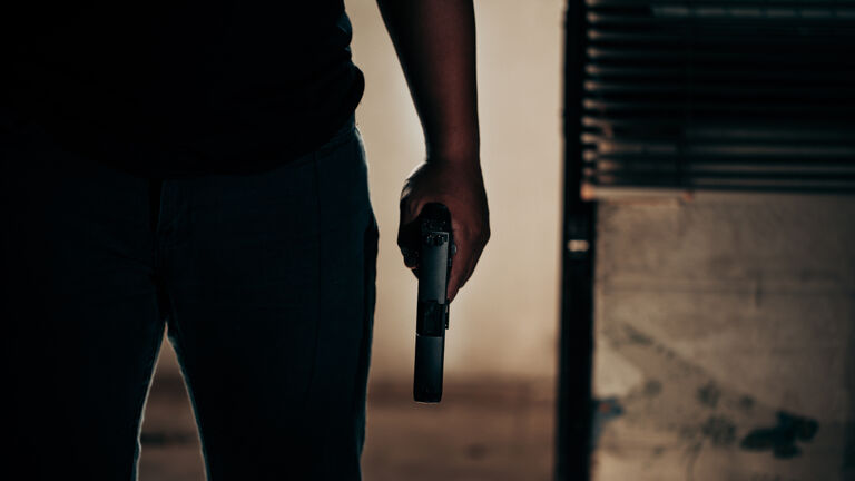 A black-shirted culprit with a gun breaks through the door of robber concept.