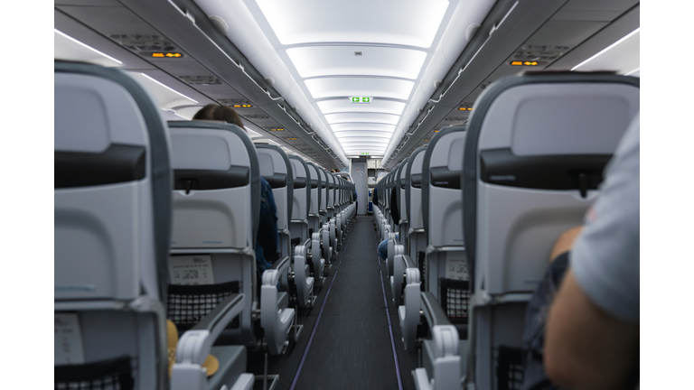 (Selective focus) View of an aircraft cabin with passengers ready for departure. Night flying, concept of travel during the Covid-19, Coronavirus pandemic.