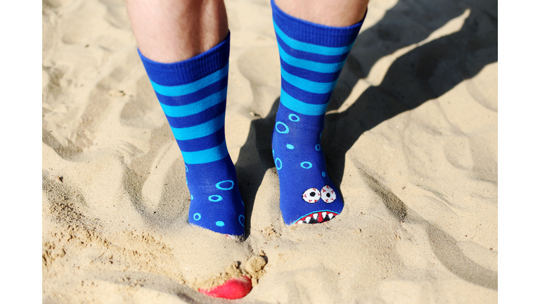 Low Section Of Person Wearing Socks Standing On Sand