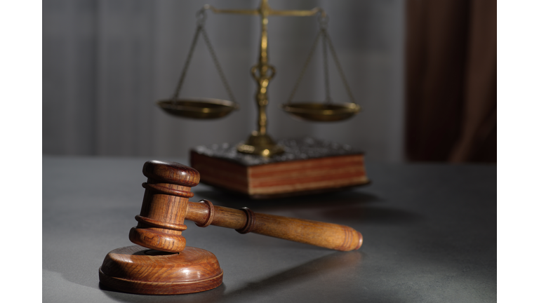 Wooden judges gavel and symbol of law and justice on table in a courtroom or law enforcement office on dark background