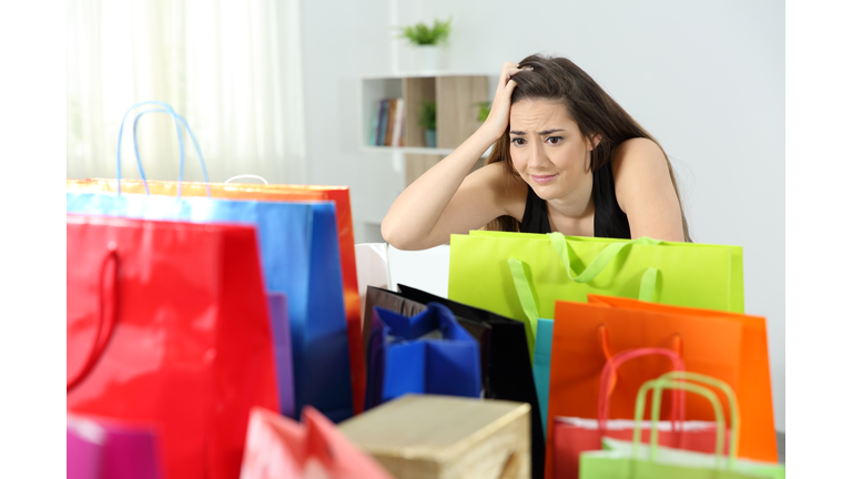 Worried shopaholic woman after multiple purchases
