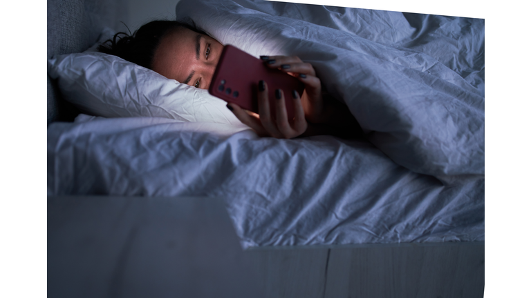 Lady messaging on smartphone in bed