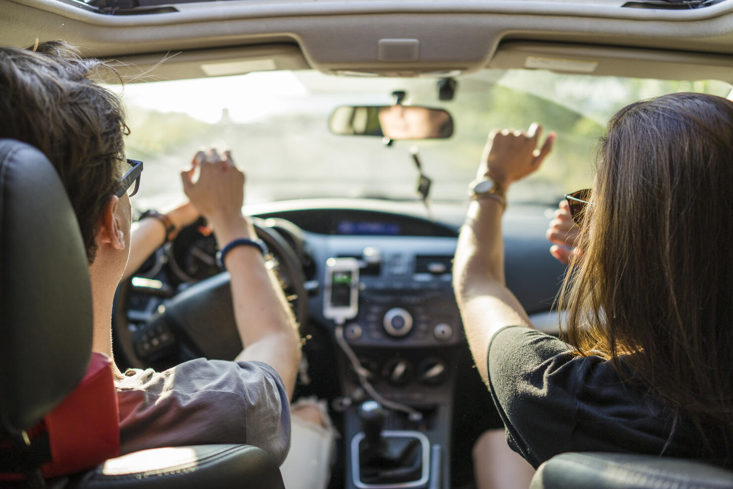 Friends dancing while on a road trip during beautiful summer day
