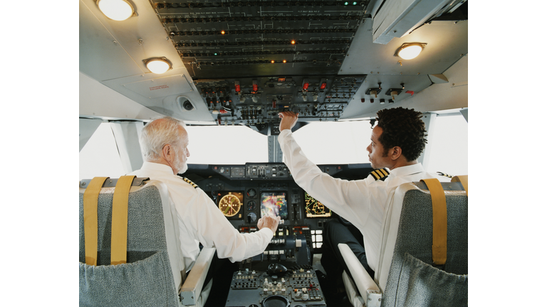 Portrait of Pilots Sitting in the Cockpit, Adjusting the Controls