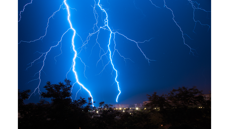 Lightning discharges during a large rainstorm in a city with forest fringes