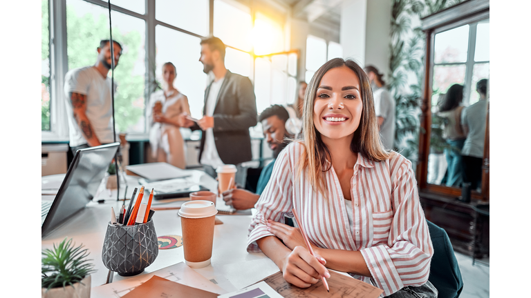 Smiling female employee sit in coworking space and working on the project