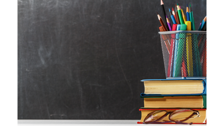 A stack of books, glasses, pencils on the background of a black school board. The concept of education. Copy space.