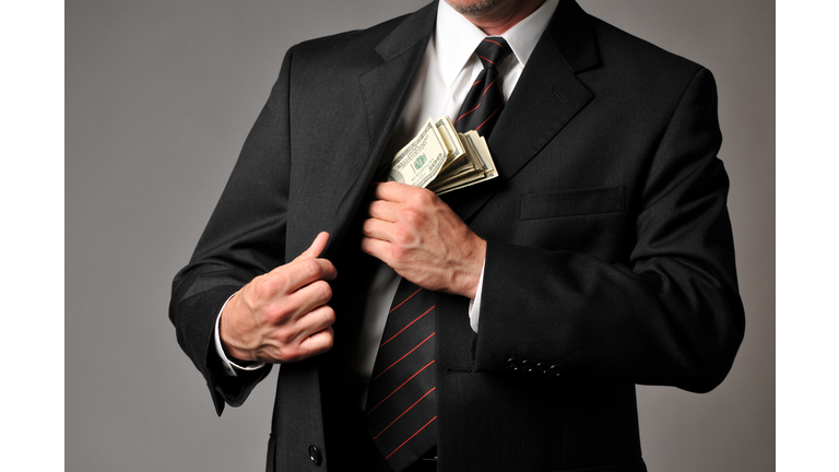 Businessman Slipping a Stack of Cash into His Suit Pocket