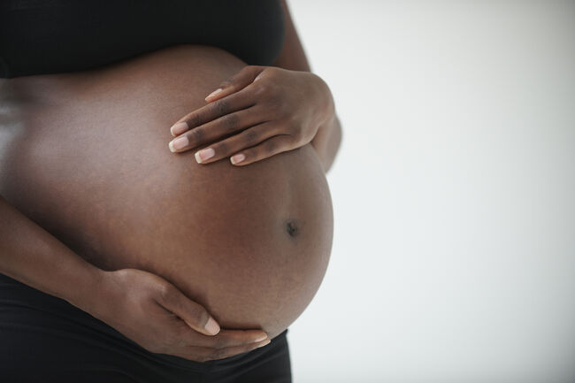 Midsection of pregnant Black woman holding belly