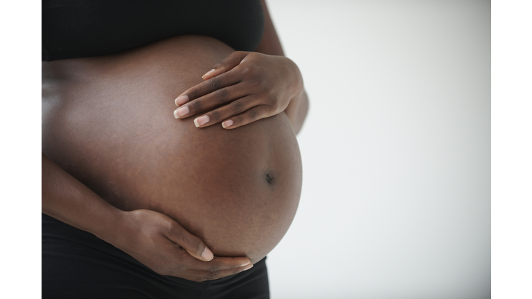 Midsection of pregnant Black woman holding belly