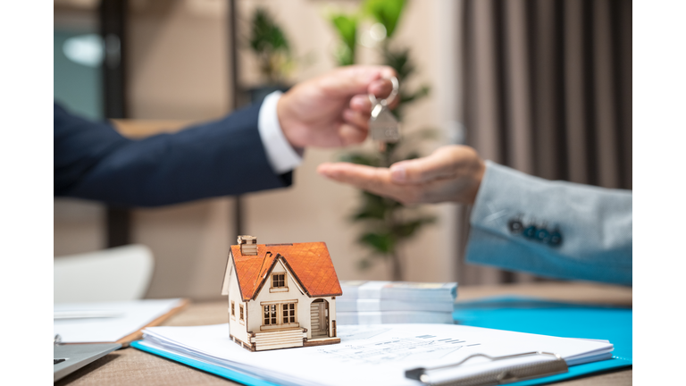 Realtor agent giving a key of apartment to new owner after signed lease agreement