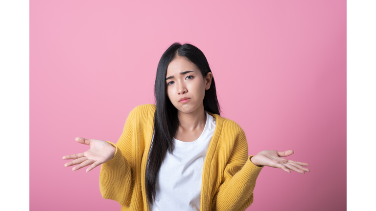 Portrait of beautiful woman who do not understand what is happening. Isolated pink background.