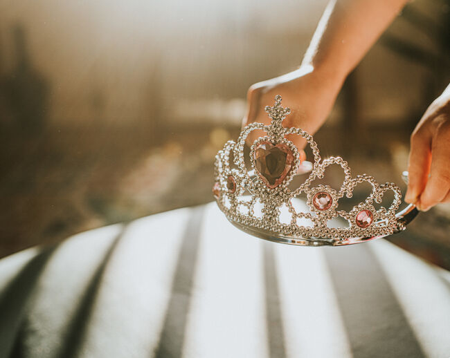 Child picking up a plastic jewelled tiara toy in sunlight