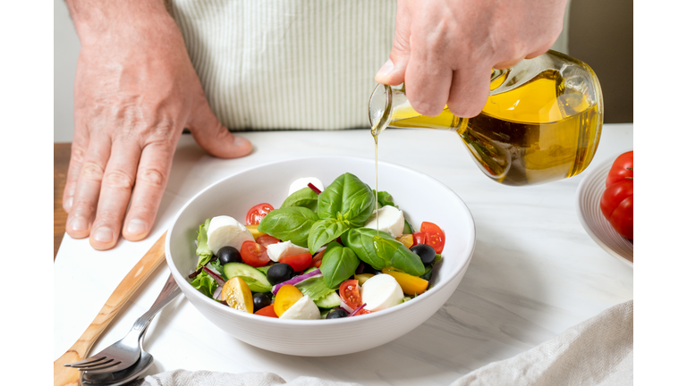 Fresh salad with cucumbers, tomatoes, onions, black olives and feta or mozzarella cheese, with olive oil and celery