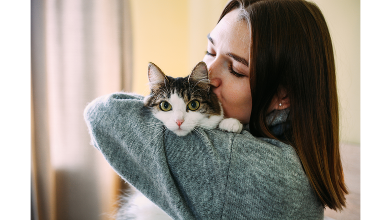 Woman at home holding her cat in hands, cozy home and pets. Cute funny animal.