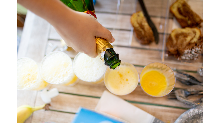 Woman pouring champagne into glasses for mimosa's